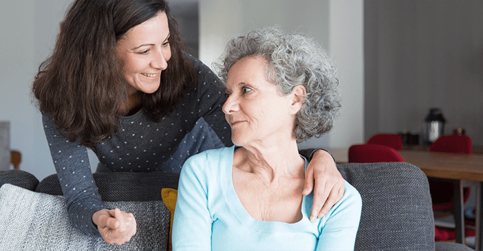 Mulher conversando com uma senhora no sofá