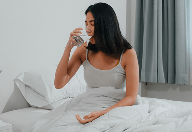 Mulher tomando água na cama